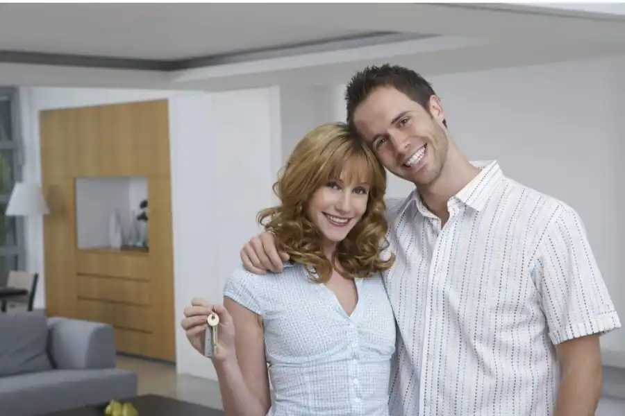 Couple Embracing and Woman Holding Keys to New Home with Big Smiles