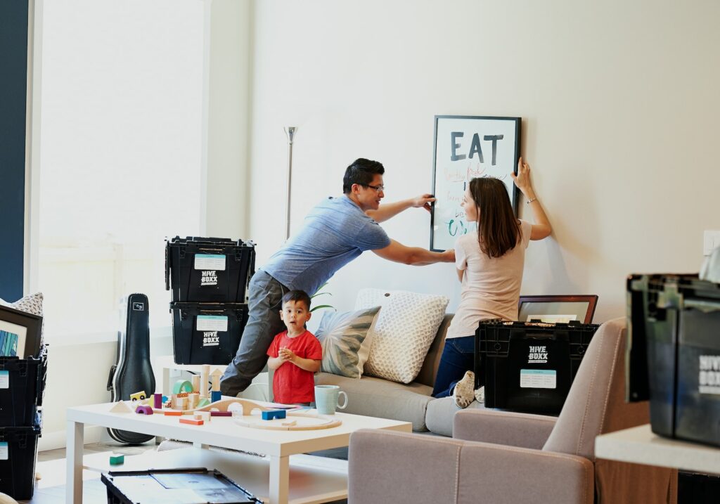 Man woman and child in new home hanging a picture